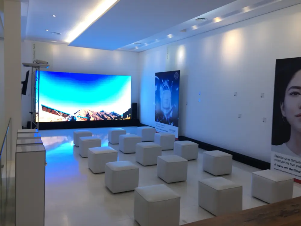 Lounge corporativo com pufes e grande painel de LED azul